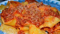 pasta with sauce and parmesan cheese on a blue and white plate sitting on a table