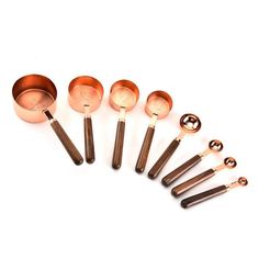 six copper measuring spoons are lined up next to each other