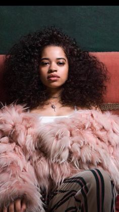 a woman sitting on top of a couch wearing a pink fur coat