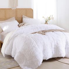 a bed with white fluffy blankets and pillows