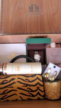 an assortment of items in a wooden box on a table next to a watch and other accessories