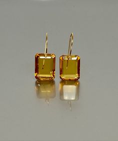 Exquisite faceted Citrine earrings featuring flawless rectangle-shaped drops. These Citrine drops showcase a flawless, rich golden hue and are gracefully attached to your choice of 24K Gold Vermeil or 14K SOLID GOLD ear wires. These earrings epitomize elegance, minimalism, and a luxurious aesthetic.A truly gorgeous pair of earrings. The earrings showcased on the mannequin serve as a visual representation of their size and proportions. When 14K SOLID GOLD ear wires are being used, the ear wire en Luxury Faceted Yellow Gold Earrings, Citrine Crystal Earrings, Luxury Modern Citrine Jewelry, Luxurious Aesthetic, Citrine Jewelry, Citrine Earrings, Classic Earrings, Yellow Earrings, Types Of Gemstones