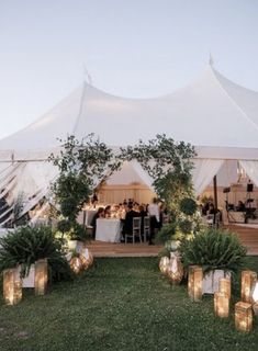 a large white tent with candles in the grass