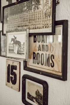 several framed pictures hang on the wall next to each other, including an old horse and room's number