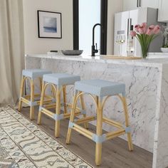 three stools in front of a counter with flowers on it and a rug next to it