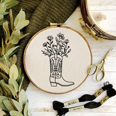 a pair of scissors sitting on top of a wooden table next to a embroidery hoop