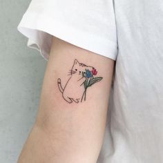 a cat with flowers on its arm is shown in this tattoo design by the artist