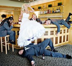 the bride and groom are laying on the floor in front of the bar with their friends