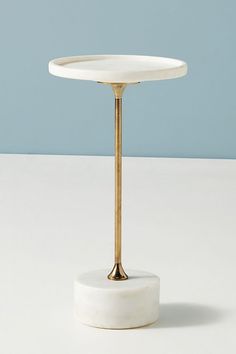 a white table with a gold plate on it and a blue wall in the background