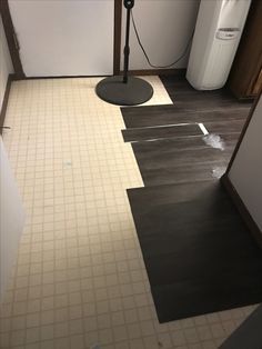 an empty bathroom with black and white tile on the floor, next to a water heater