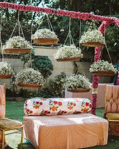 an outdoor seating area with flowers hanging from the ceiling and chairs on the ground,