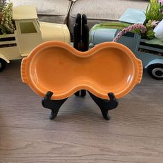 an orange plate sitting on top of a wooden table next to toy cars and flowers