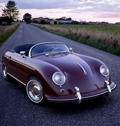 an old style car is parked on the side of the road in front of a grassy field