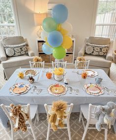 a baby's first birthday party with balloons and stuffed animals on the table in front of them