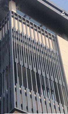 the side of a tall building with metal slats on it's sides and windows