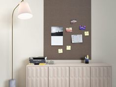 a room with a lamp, cabinet and bulletin board on the wall next to it