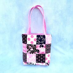 a pink and black patchwork tote bag sitting on top of a blue background