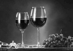 two wine glasses sitting on top of a table next to grapes