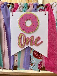 there is a sign that says one with a donut on it and ribbons around it