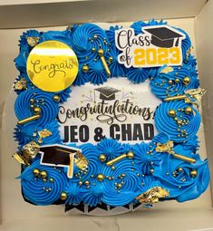 a graduation cake with blue icing and gold decorations on it's side in a box