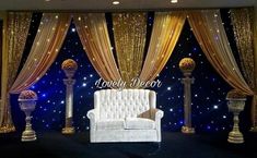 an elegant stage set up with gold drapes and white couches in the center