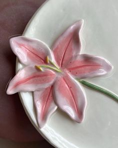 a pink flower is sitting on a white plate