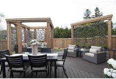 a table and chairs on a wooden deck next to an outdoor dining area with white flowers