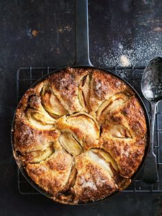 a pie sitting on top of a cooling rack next to a fork and spoons