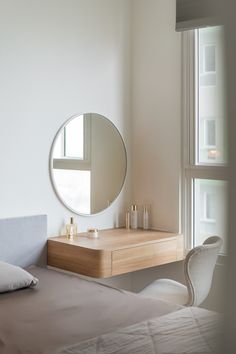 a bedroom with a bed, dresser and mirror in it next to a large window