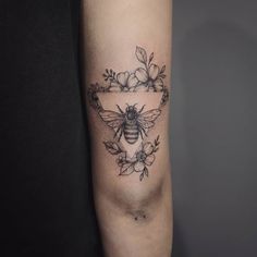 a black and white photo of a bee with flowers on it's arm, in the shape of a frame