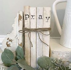 a wooden block with the word pray tied to it next to some flowers and leaves