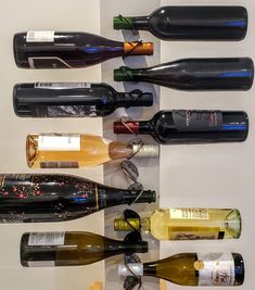 several bottles of wine are lined up in a row on the wall next to each other