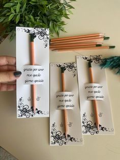 three pieces of paper with writing on them next to some pencils and a potted plant