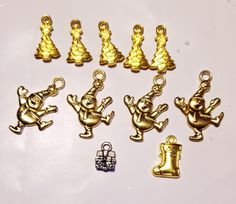 some gold colored charms are sitting on a white surface and one is wearing a santa hat