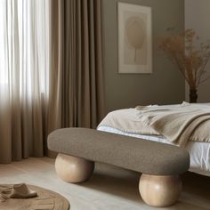 a bedroom with a large bed and wooden foot stools in front of the window