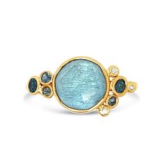 a gold ring with an oval blue stone surrounded by three small white and yellow diamonds