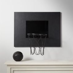 a basketball hoop mounted to the side of a white wall next to a black ball