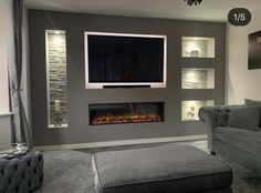 a living room with a couch, chair and television mounted on the wall above it