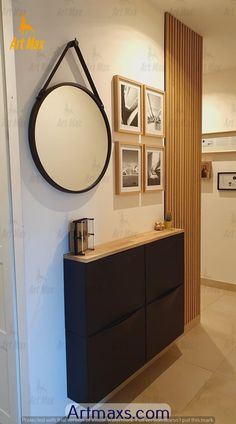 a bathroom with a black cabinet and pictures on the wall above it, along with a round mirror