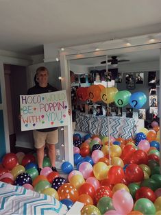 a man holding a sign surrounded by balloons