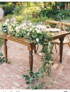 an outdoor table with flowers and greenery on it