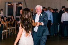 an older man and woman dancing together at a wedding