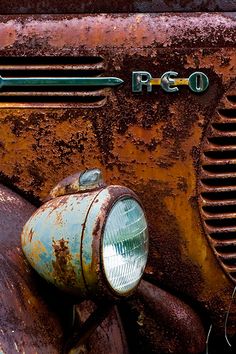 an old rusted out truck with a light on it's headlight is shown