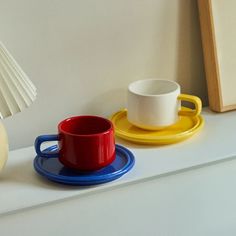 two cups and saucers are sitting on a shelf