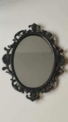 a round mirror hanging on the wall next to a white wall with a black frame