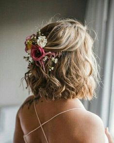 the back of a woman's head with flowers in her hair, wearing a strapless dress