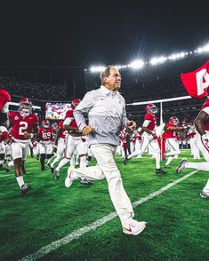 the football team is running onto the field with their coaches in red and white uniforms