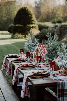 a picnic table set up with plates and place settings for christmas dinner in the park