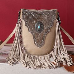 Made of PU leather, this western crossbody has: Cowhide on the front Accented with turquoise stone concho medallion Antique silver embellishments Fringe Top zipper closure Inside zippered compartments have a zippered pocket and an open pocket A zippered pocket on the back Lobster clasp which can convert to clip bag Detachable adjustable shoulder straps (48") 7" x 2" x 8" (Drop 24") Western Leather Bags With Concho Details, Bohemian Leather Bag With Concho, Western Style Brown Bag With Concho, Bohemian Brown Bags With Concho, Western Bags With Concho Detail, Western Style Bags With Concho, Western Style Bags For Festivals, Western Style Crossbody Shoulder Bag For Travel, Western Leather Crossbody Shoulder Bag