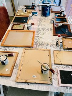 the table is set up with many different types of frames and paintbrushes on it